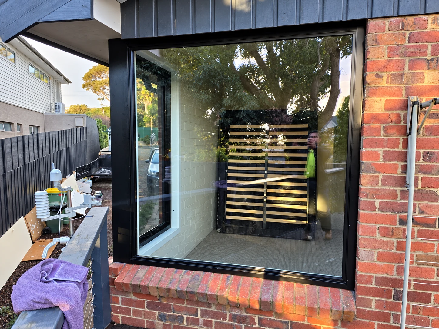 Black aluminium corner glazing in a red brick wall beside a timber deck