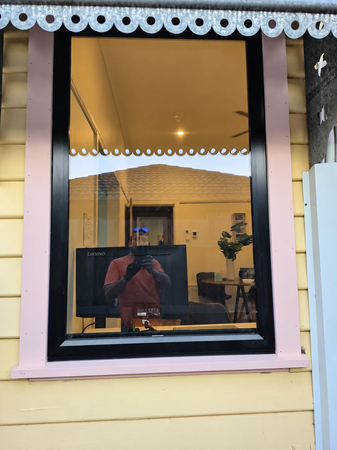 Tall dark framed window with a pale surround and scalloped outdoor awning