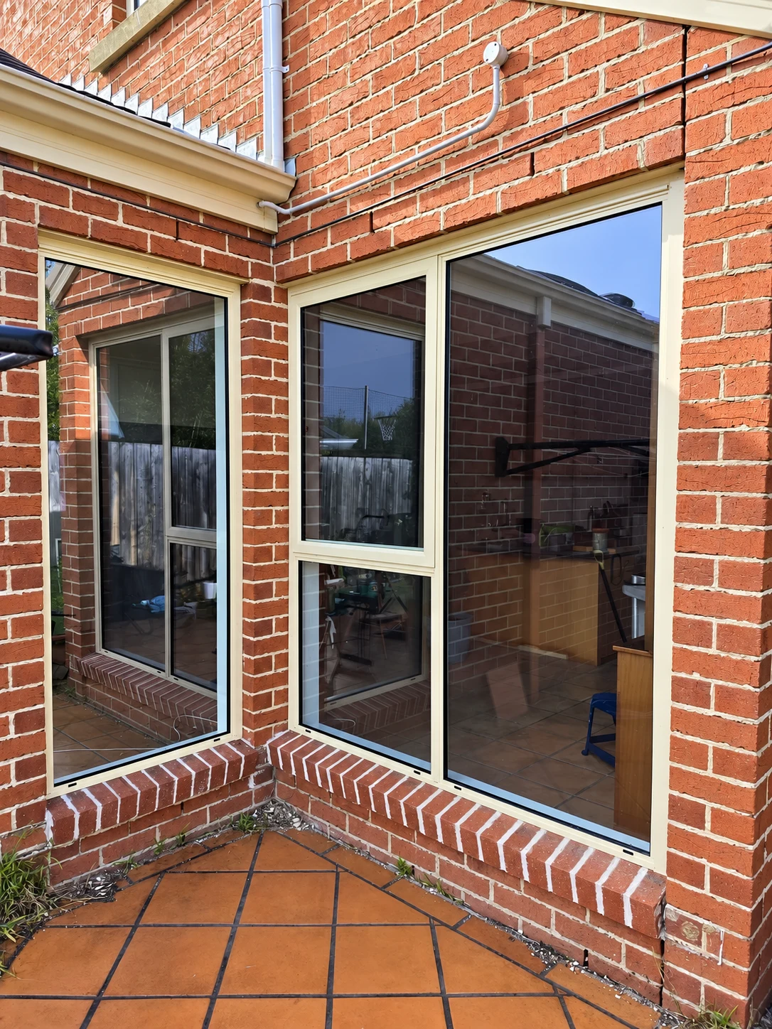 White framed glazing meeting at the inside corner of a red brick exterior wall