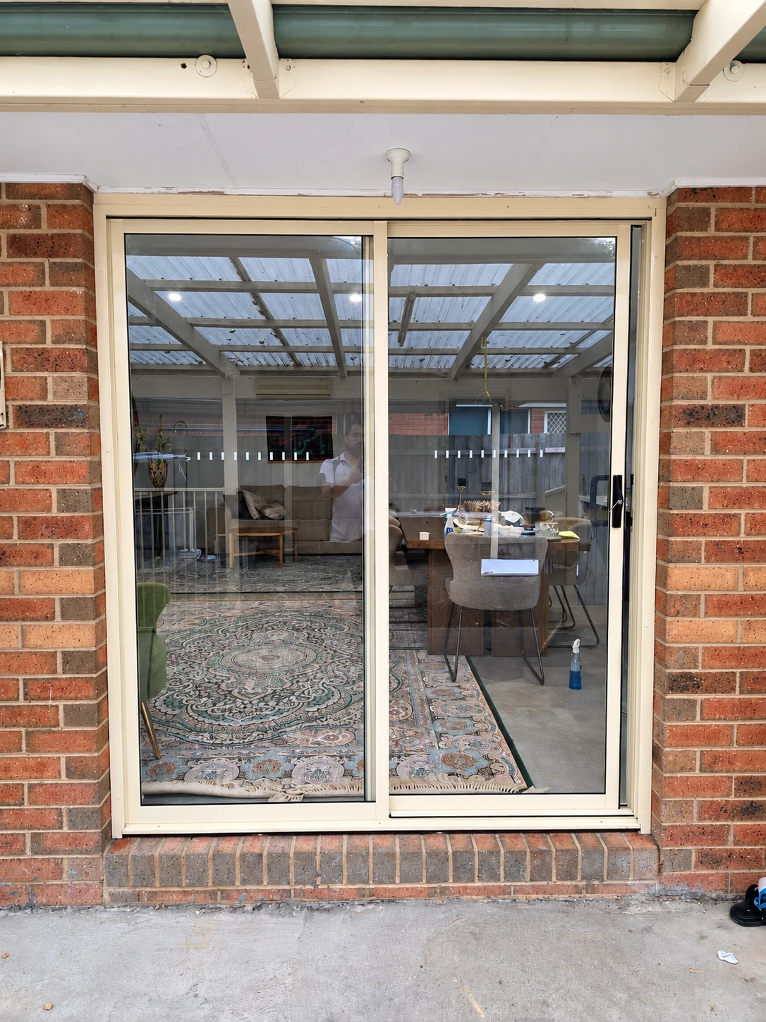 White framed two-panel glazed door beneath a covered patio beside red brickwork