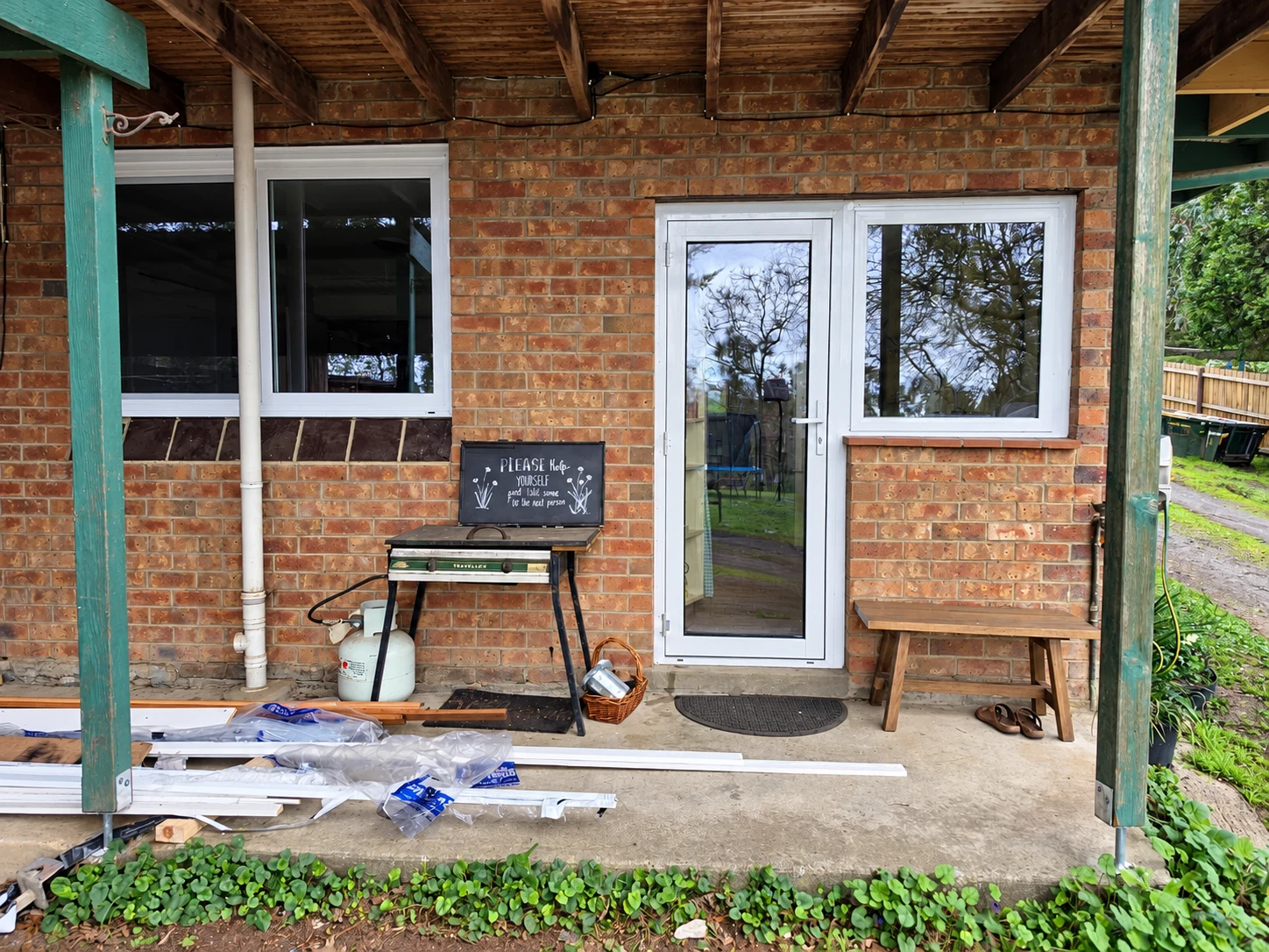 White framed glass door and windows beneath a timber verandah during installation finishing work